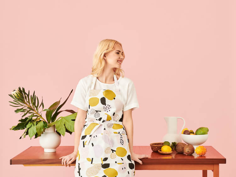 Woman wearing Kauniste´s Tutti Frutti apron, designed by Hannele Äijälä